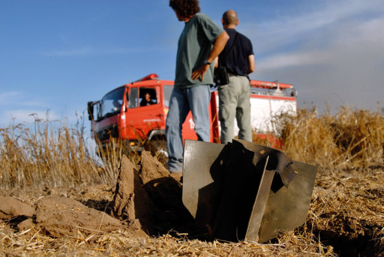 Israeli security personnel stand near the remains of a rocket outside the northern Gaza Strip