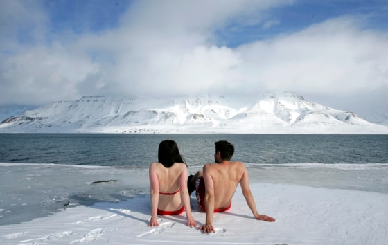 Climate activists Lesley Butler and Rob Bell \"sunbathe\" on the edge of a frozen fjord in the Norwegian Arctic town of Longyearbyen