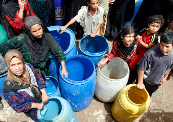 Iraqi displaced wait for their containers to be filled with water
