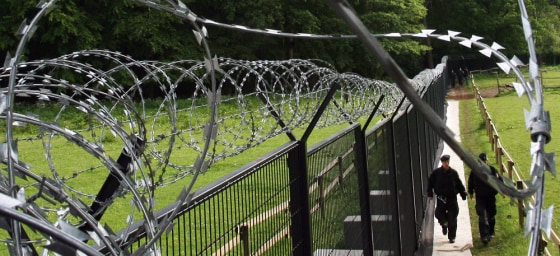Policemen walk past the fence surroundin