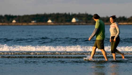 Friends enjoy a late afternoon walk at Popham Beach State Park, in Phippsburg, Maine.