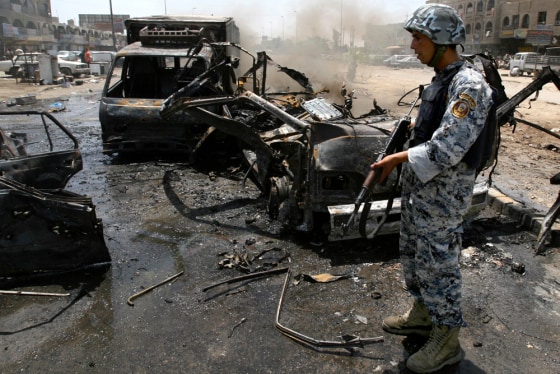An Iraqi policeman stands beside vehicles destroyed after a bomb placed under a parked car exploded Thursday outside a restaurant in the Shiite enclave of Sadr City in Baghdad, Iraq, police said.