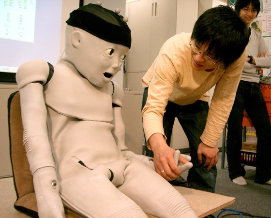 The Child-Robot with Biomimetic Body, or CB2, looks at Shuhei Ikemoto, an Osaka University student, when its hand is clasped by him during a demonstration of the toddler robot at a lab of the university in Osaka, western Japan.