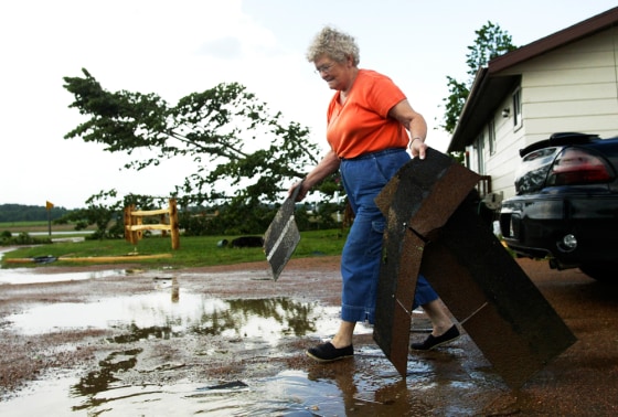Marcella Kasper picks up shingles from her driveway Thursday in Reid, Wis., after a tornado touched down near her home.