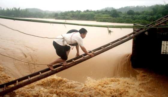 A man tries to climb to a floodgate to unlock a valve in Zijin County of south China's Guangdong province June 9.