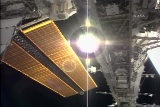 The international space station's new solar panels gleam golden alongside the truss structure installed by spacewalkers this week — with the sun shining through a gap.