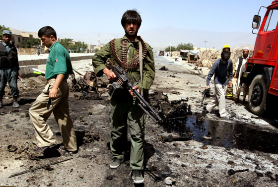 An Afghan security man carries his heavy machine gun Saturday as he walks around the site of a suicide attack in Kabul, Afghanistan.