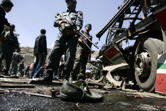 An Afghan Police officer (C) secures an