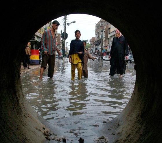 People walk through a flooded street after heavy rains in Hyderabad
