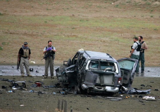 Western security guards stand near the wreckage of a car that was blown up by a Taliban suicide bomber in the Afghan capital of Kabul