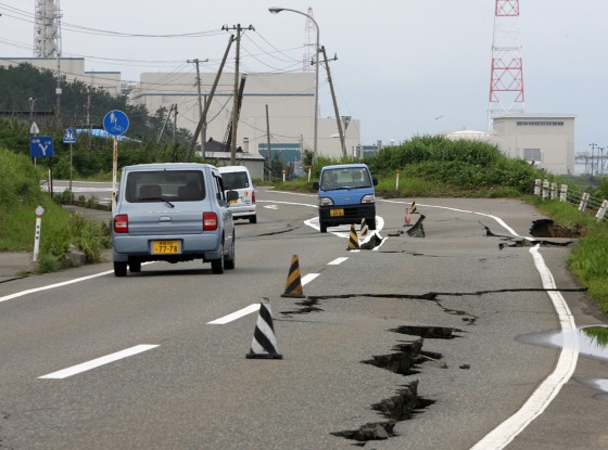 Vehicles drive on a damaged road leading