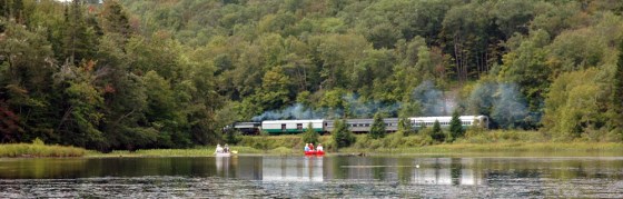 Canoeists watch the Adirondack Scenic Railroad train as they paddle on Moose River outside Old Forge, N.Y.