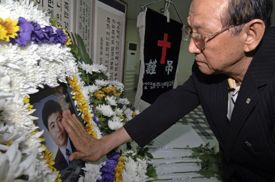 An acquaintance of pastor Bae Hyung-gyu touches a portrait of Bae in Jeju on Jeju Island