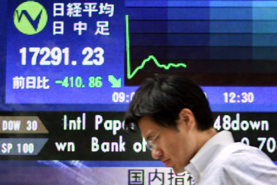 A man walks past a share prices board in