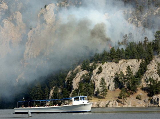 A tour boat on the Missouri River passes a wildfire in Montana's Gates of the Mountains Wilderness. The fire had ballooned by nearly 8 square miles to 17.7 square miles Sunday, and was expected to keep growing Monday in similar "extreme" conditions.