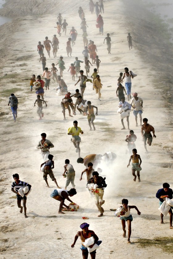 Villagers run to receive relief packages air dropped for flood victims at Darbhanga district, in the northern Indian state of Bihar, on Saturday.