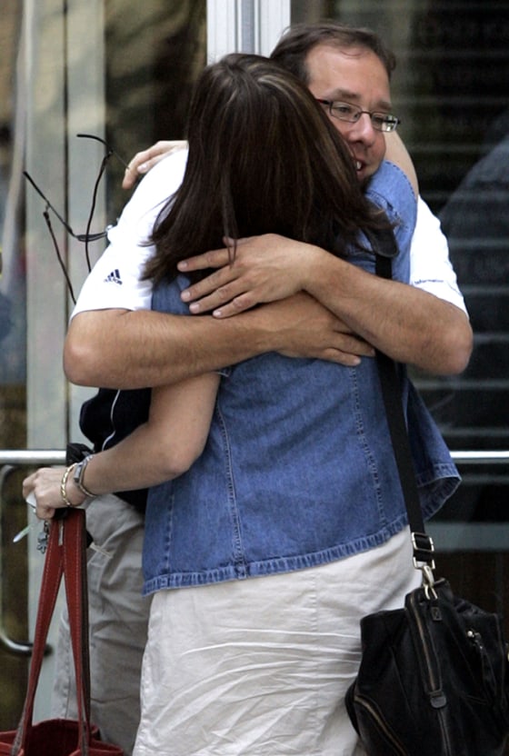 Employees hug each other as they leave the building of American Home Mortgage Investment Corp. in Melville, New York.