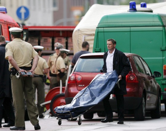 A undertaker pushes a body in a body bag to a hearse