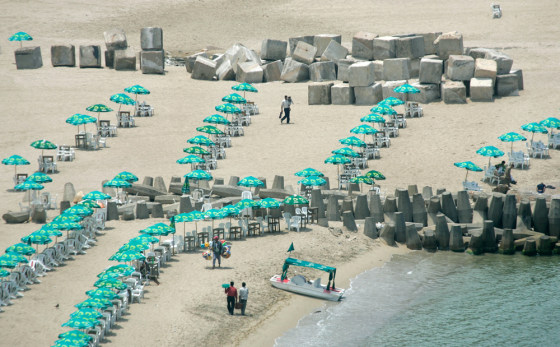 Large concrete blocks used in the construction of sea defenses intermingle with the umbrellas and beach chairs of tourists on the beach in Alexandria, Egypt, on May 15. The Mediterranean Sea is creeping higher, flooding parts of the Egyptian shoreline.