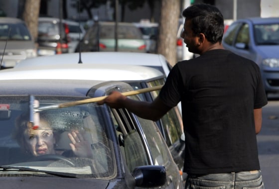 A woman in Rome signals that she doesn't want her windshield cleaned at a traffic light on Wednesday.