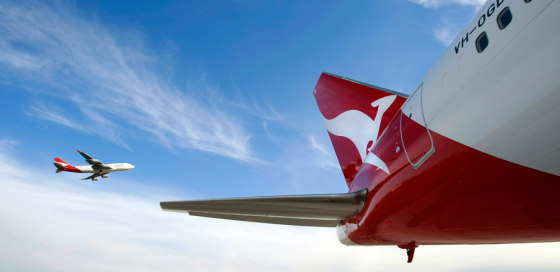 Qantas Boeing 747 flies past a 767 airplane with a newly unveiled Qantas logo on its tail in Sydney