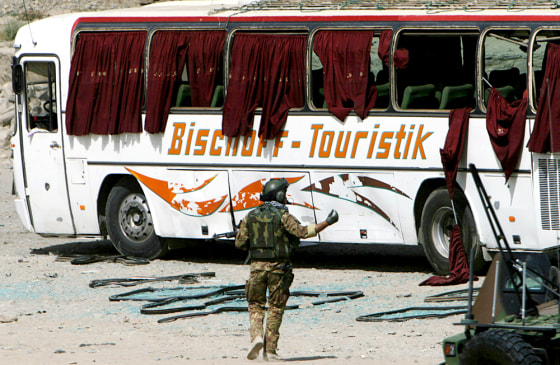 A soldier of the International Security Assistance Force walks near a civilian bus that was damaged in a car bomb blast in western Kabul on Friday.