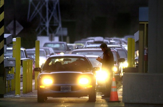 A US Customs officer (R) is on duty as cars line u