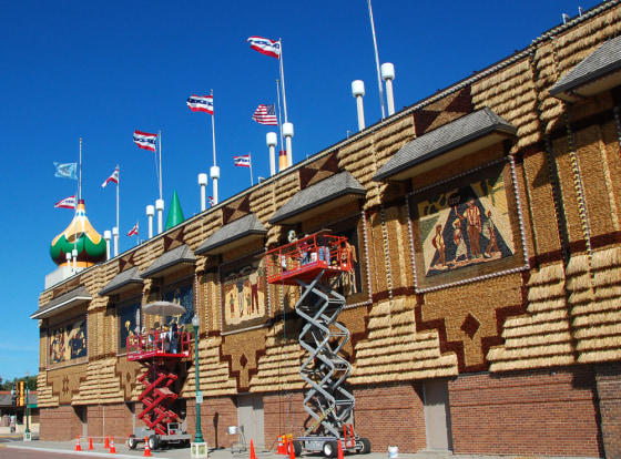 Workers on scissor lifts create murals out of corn on the side of the Corn Palace in Mitchell, S.D. Since the Corn Palace debuted in 1892, its palette has grown to 12 distinct shades of corn.