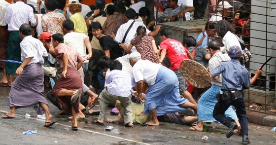 A riot policeman charges at a crowd attempting to disperse after police and military officials fired upon protesters taking to the streets of Yangon