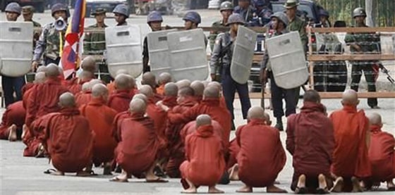 Buddhist monks pray at a roadblock in Yangon, Myanmar, on Thursday. About 10,000 anti-government protesters gathered in downtown Yangon despite a violent crackdown by security forces that drew international appeals for restraint by Myanmar&#x27;s ruling junta.