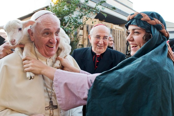 Image: A woman dressed as a character from a nativity scene puts a lamb around the neck of Pope Francis.