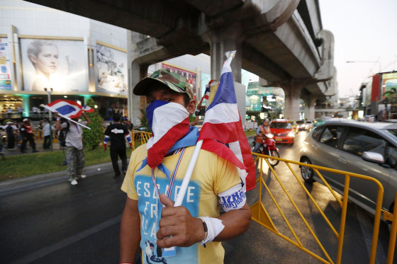Image: An anti-government protester mans a barricade across a major intersection in central Bangko