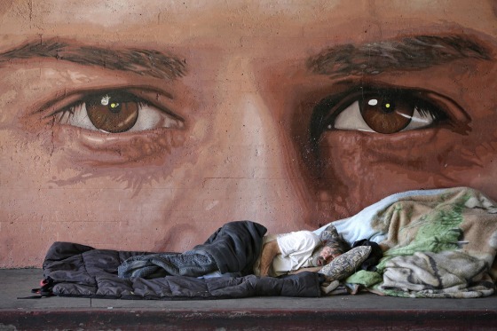 Image: A homeless man naps in front of a mural painted by artist Ruben Soto on Friday in Los Angeles.