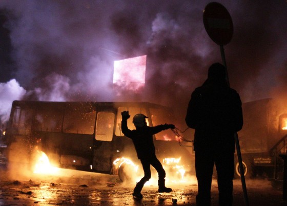 Image: Protesters clash with riot police next to a bus in flames in Kiev.