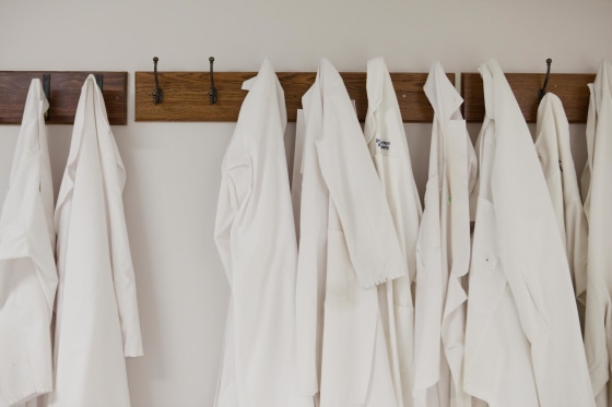 Lab coats hang in a row at a hospital. New guidance suggests that doctors and other health workers launder their coats at least once a week and hang them on hooks when they're actually examining patients.