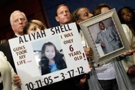 Diana Aguilar (L) and Tonya Burch (R) hold photos of their children during a press conference at the U.S. Capitol calling for gun reform legislation