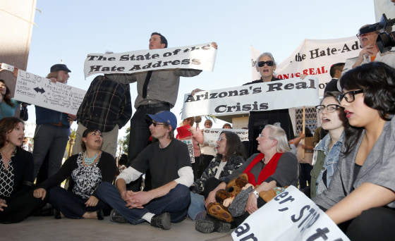 Immigration rights protesters sit out in front of the House of Representatives after Arizona Gov. Jan Brewer gives her State of the State address at the Arizona Capitol Monday, Jan. 13, 2014, in Phoenix.