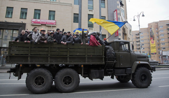 Image: Protesters ride atop of what appears to be a military truck in central Kiev, Ukraine