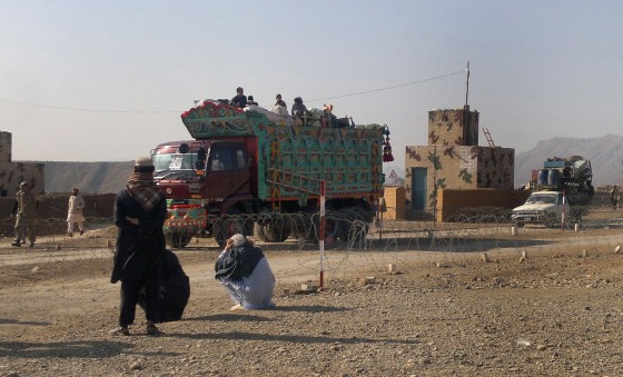 Image: Pakistani tribal families crossing a military check post as they flee after air strikes on Taliban hideouts