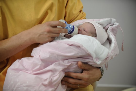 Image: A man gives the feeding bottle to his newborn baby at the maternity of the Angers hospital in Angers, western France