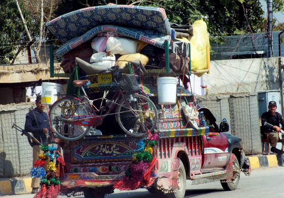 Pakistani policemen watch a vehicle carrying internally displaced Pakistani tribal civilians, fleeing from military operations against Taliban militants in North Waziristan.