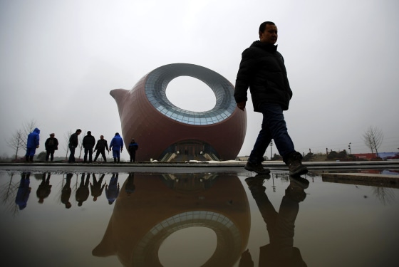 Image: Workers stand next to a building shaped like a clay teapot in Wuxi