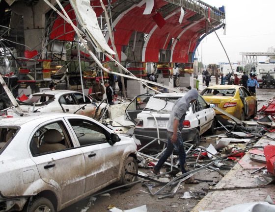 Image: A youth walks past the site of a bomb attack in the city of Hilla