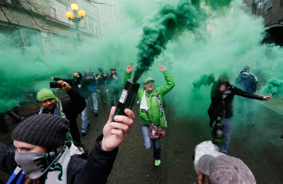 Image: Members of the Emerald City Supporters and other fan groups burn smoke devices as they take part in the traditional \"March to the Match\" before the Seattle Sounders season-opening MLS soccer match