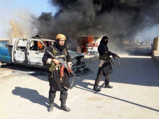 This undated image posted on a militant website on Jan. 4, 2014, shows Shakir Waheib, a senior member of the al Qaeda-linked Islamic State of Iraq and the Levant (ISIL), left, next to a burning police vehicle in Iraq's Anbar province.