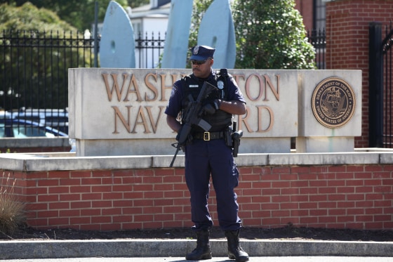 Image: A Navy employee who did not want to be identified lays flowers near the main gate to the Washington Navy Yard.