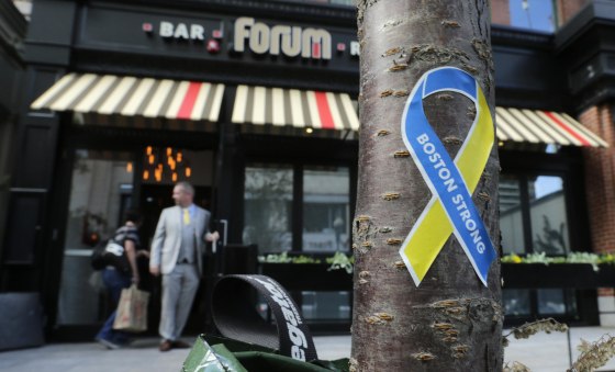 A "Boston Strong" sticker is stuck to the trunk of a tree as a manager opens the door for a worker outside the Forum restaurant and bar near the finish line of the Boston Marathon, in Boston, on Aug. 15, 2013. The restaurant, which was damaged after one of the bombs exploded in front of the building, reopened Thursday, for a private event, for the first time since the race.