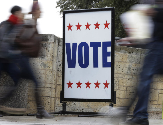 Image: Pedestrians pass voting signs near a voting sign.