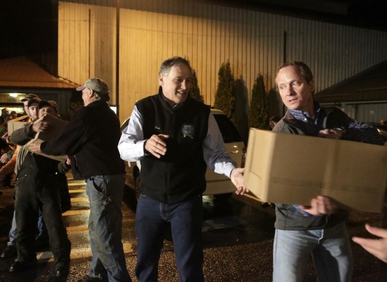 Washington Gov. Jay Inslee helps community members unload a truckload of donated goods at the Community Center in Darrington, Wash.