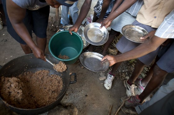 Image: Students hold out their plates as the school cook ladles out a bulgur wheat and bean dish at a public school in Bombardopolis, Haiti.